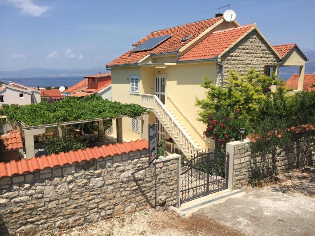 a house with a stone wall and a fence at Villa Radoš - 4 Sterne, 4 Apartments für maximal 22 Gäste in Supetar