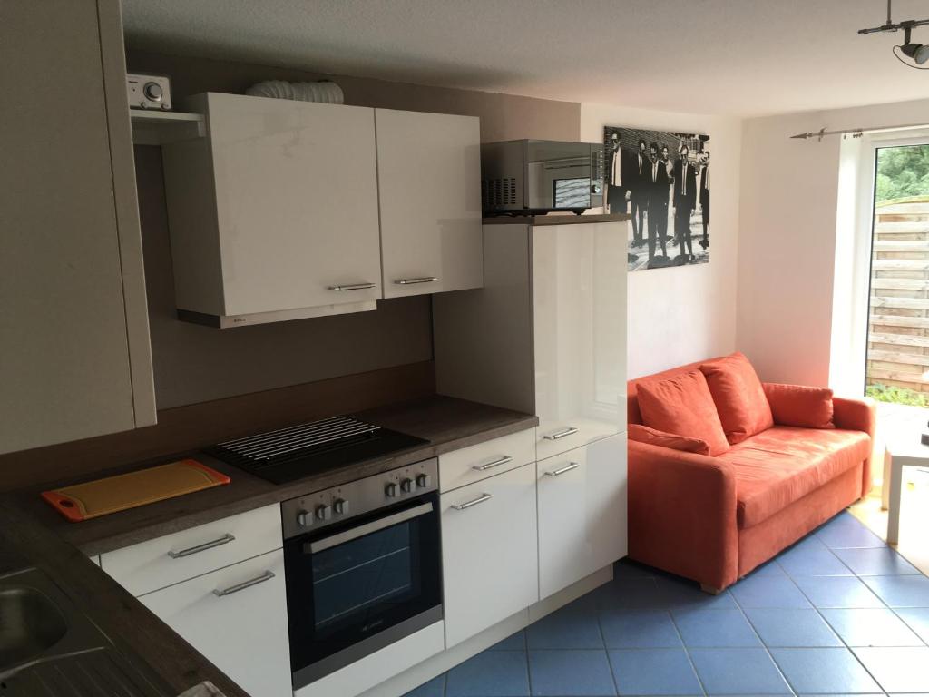 eine Küche mit weißen Schränken und einem orangefarbenen Stuhl in der Unterkunft Ferienwohnung Ulmrich in Kesselbach