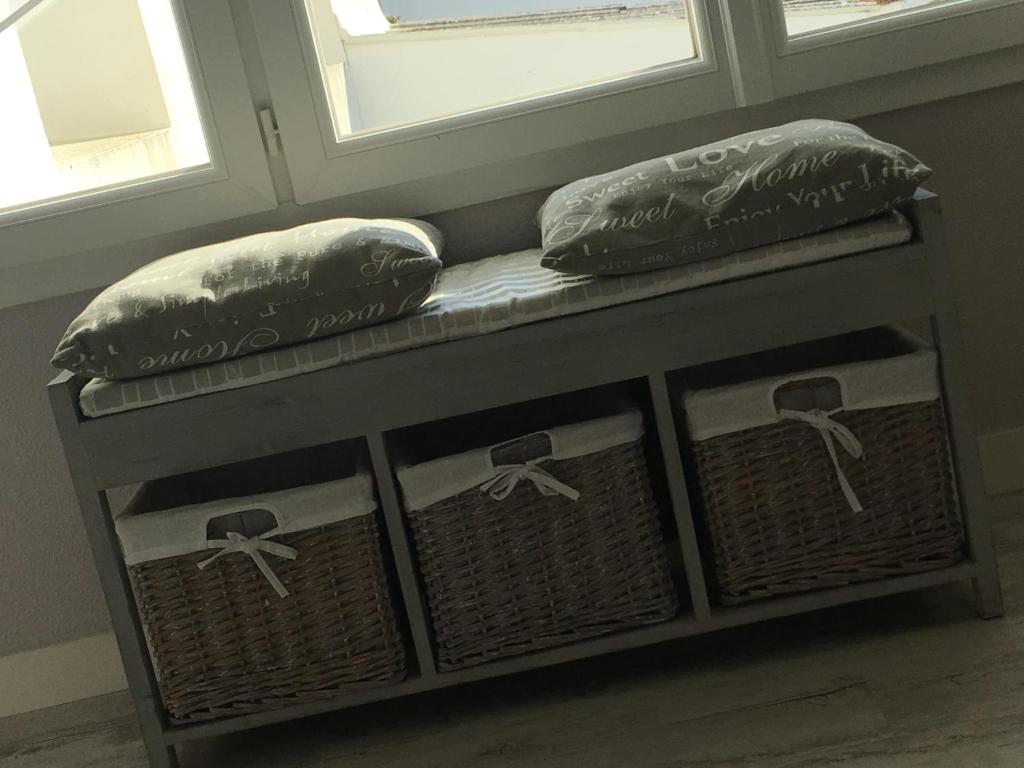 un banco con dos almohadas junto a dos ventanas en Mes Ptits Apparts, en La Cotinière