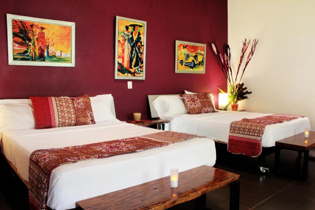 two beds in a room with red walls at Oasis de las Palmas in Ojochal