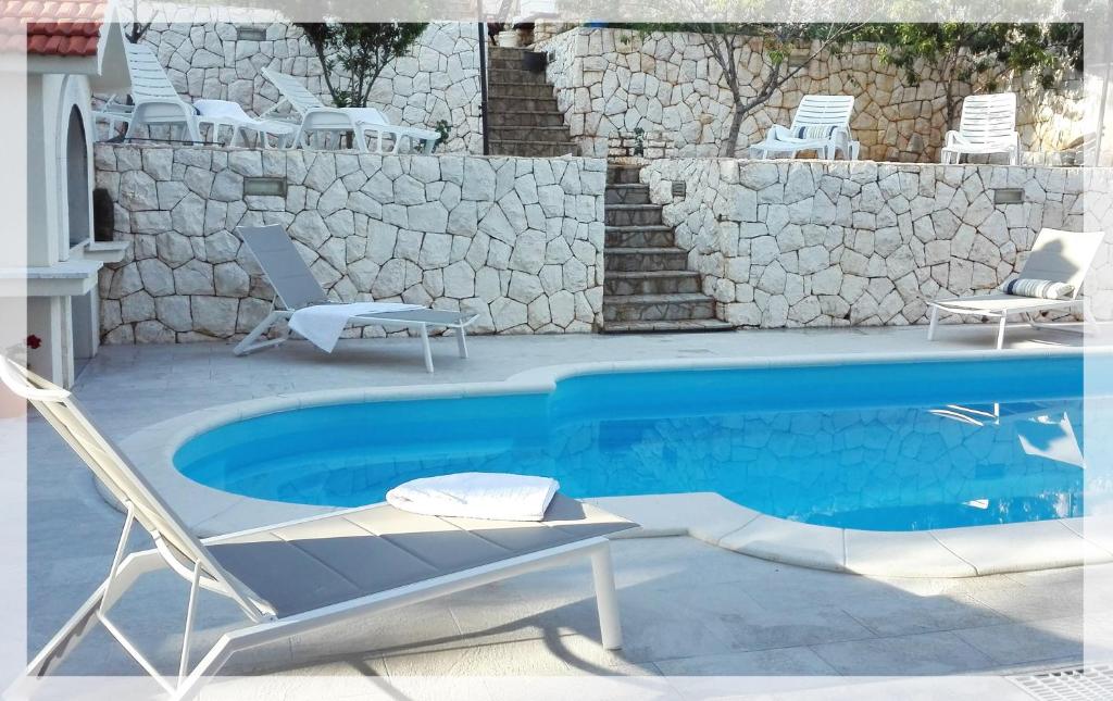 a swimming pool with two chairs and a table and a chair at Apartment with pool near Split in Split