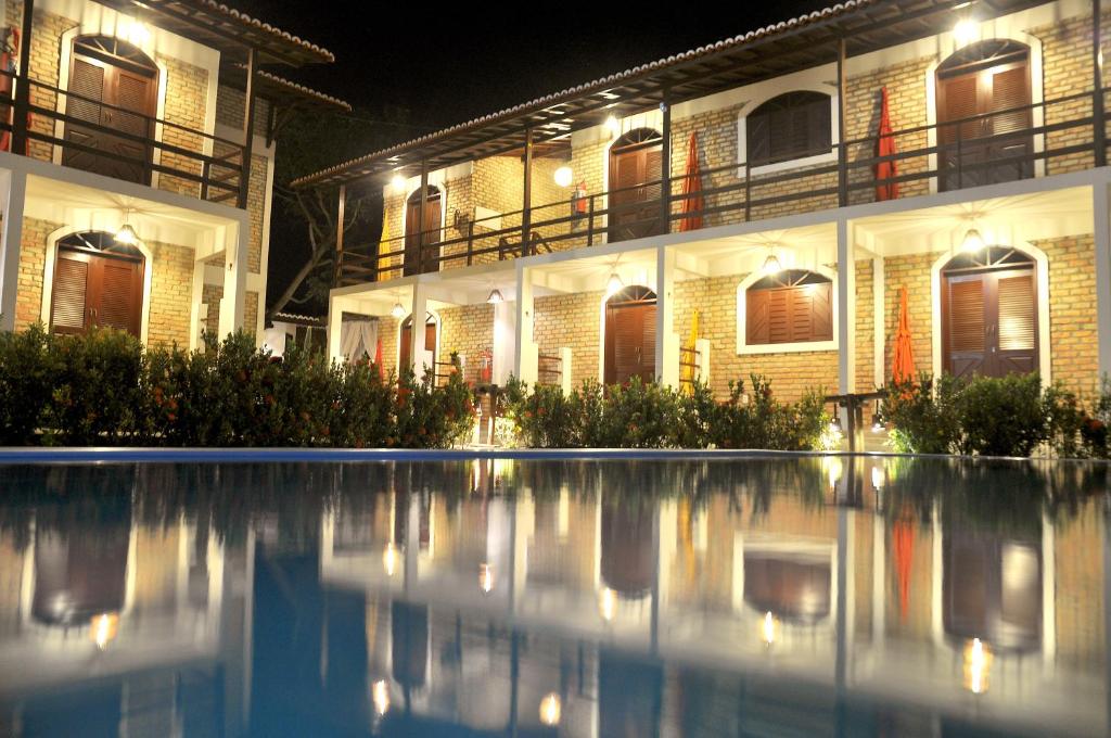 a building with a swimming pool at night at Oxente Travel Apart Hotel in Natal