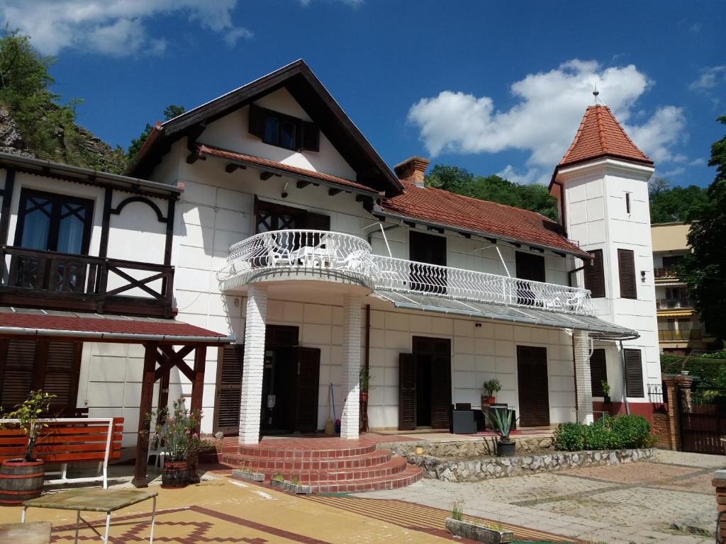 a white house with a tower and a balcony at Valcsics Villa Panzió in Pécs