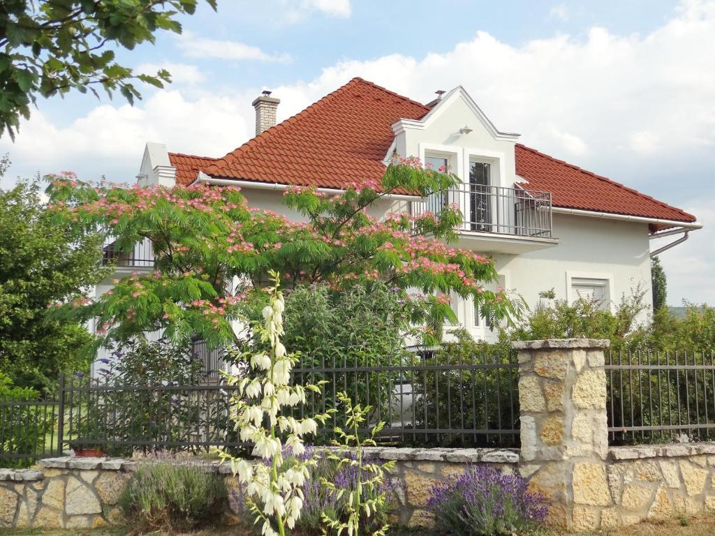 una casa blanca con una valla y flores en Albízia Apartments, en Balatonfüred
