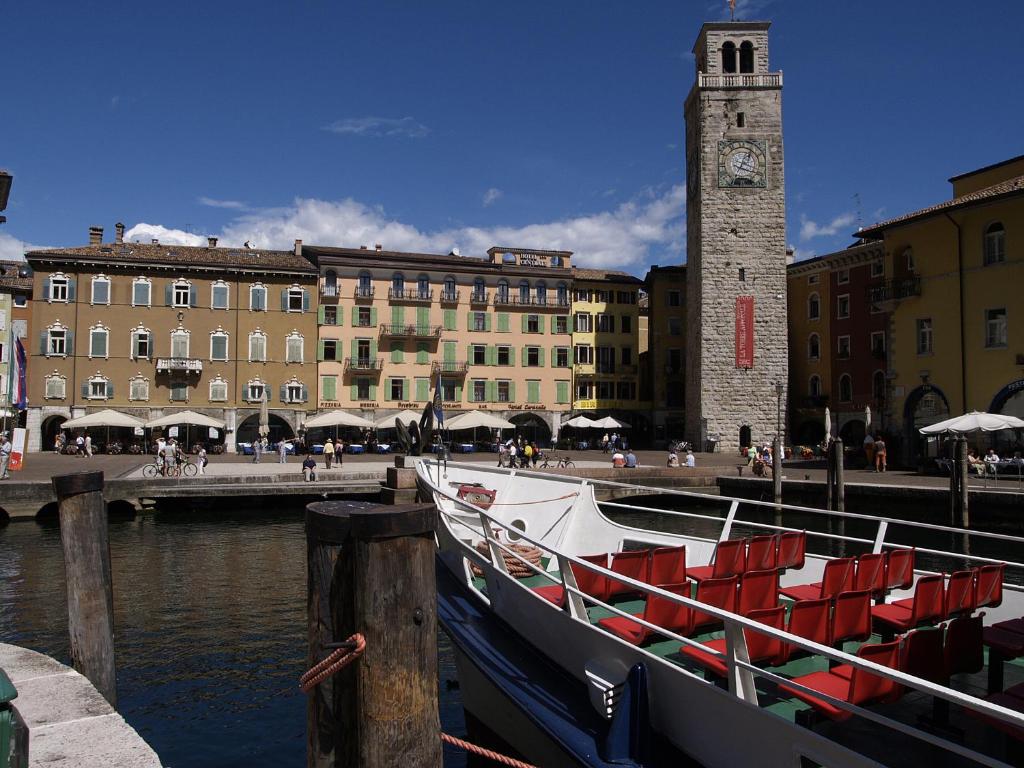un barco atracado en un muelle con una torre de reloj en Hotel Centrale, en Riva del Garda