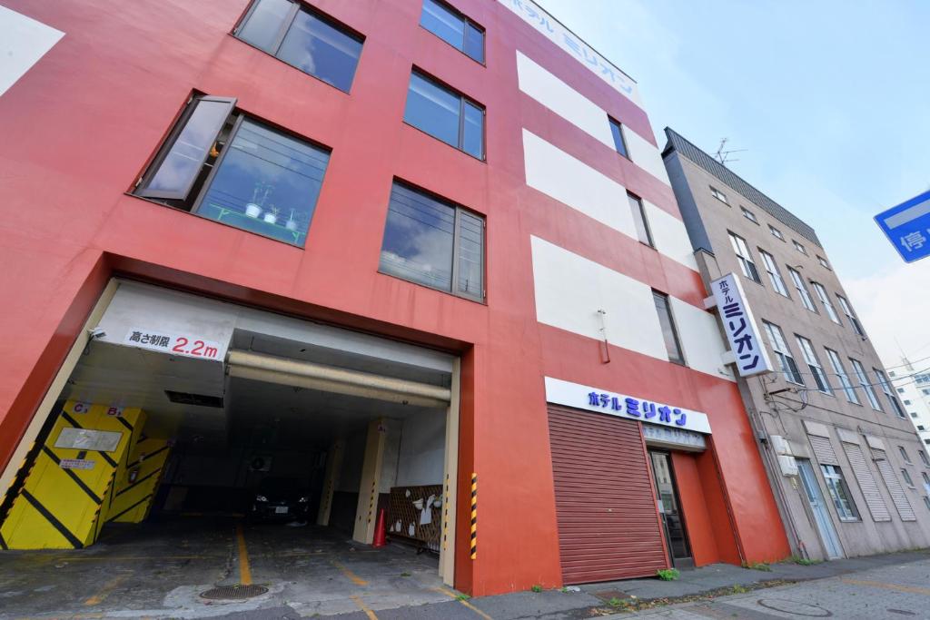 a red building with a garage in front of it at Hotel Million in Muroran
