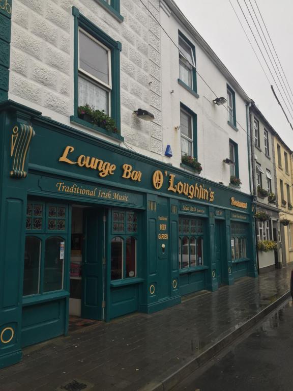 un edificio con una tienda verde en una calle en O'Loughlin's Bar, en Miltown Malbay