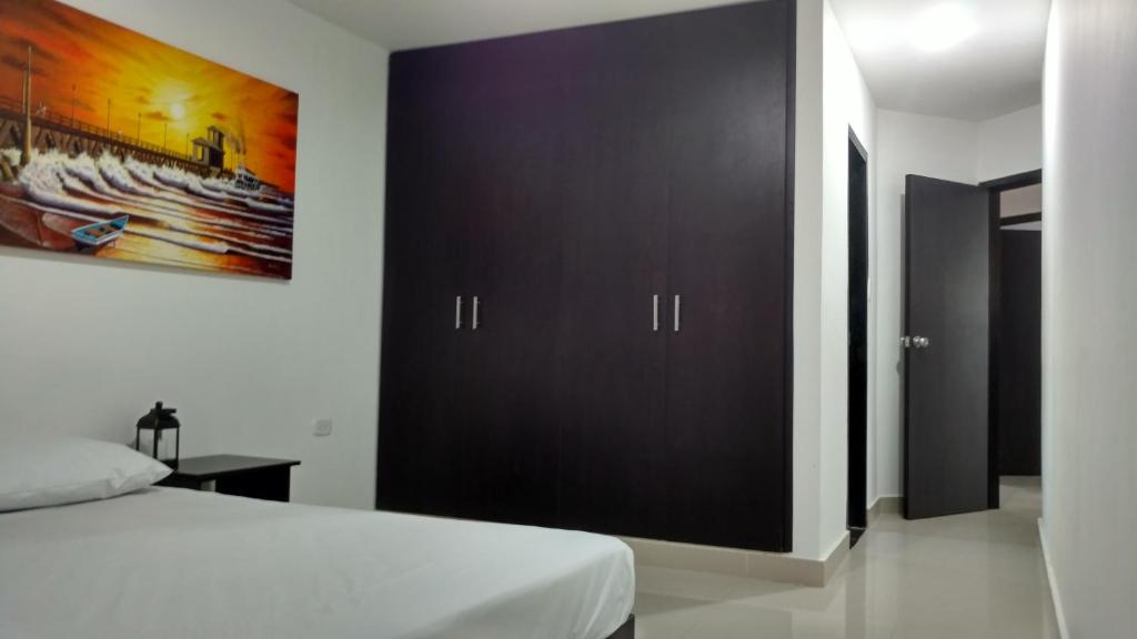 1 dormitorio con 1 cama y armario negro grande en Hotel El Emigrante, en Puerto Colombia