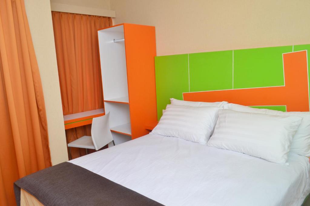 1 dormitorio con 1 cama con cabecero naranja y verde en Titanium Express HomTel en Yakarta