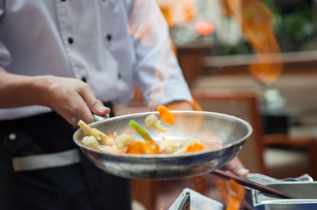 a person holding a bowl of food with vegetables at Surabaya Suites Hotel Powered by Archipelago in Surabaya