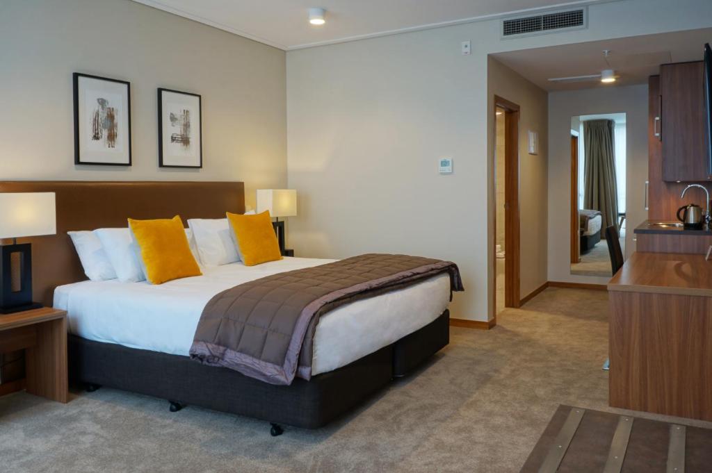 a bedroom with a large bed with yellow pillows at The Victoria Hotel Dunedin in Dunedin