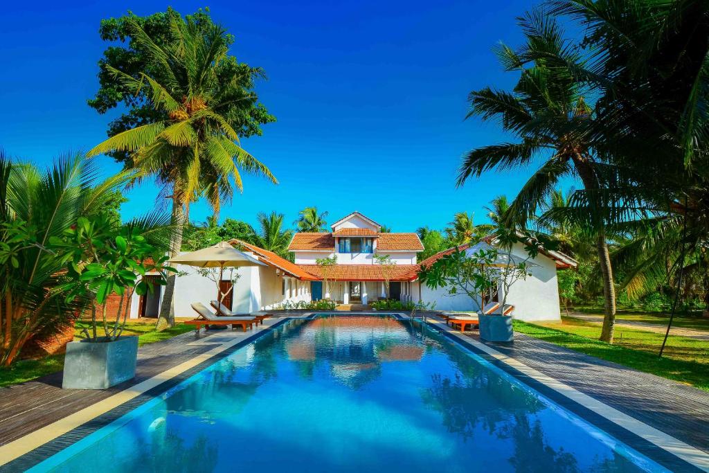 a villa with a swimming pool in front of a house at Handun Villas in Talalla