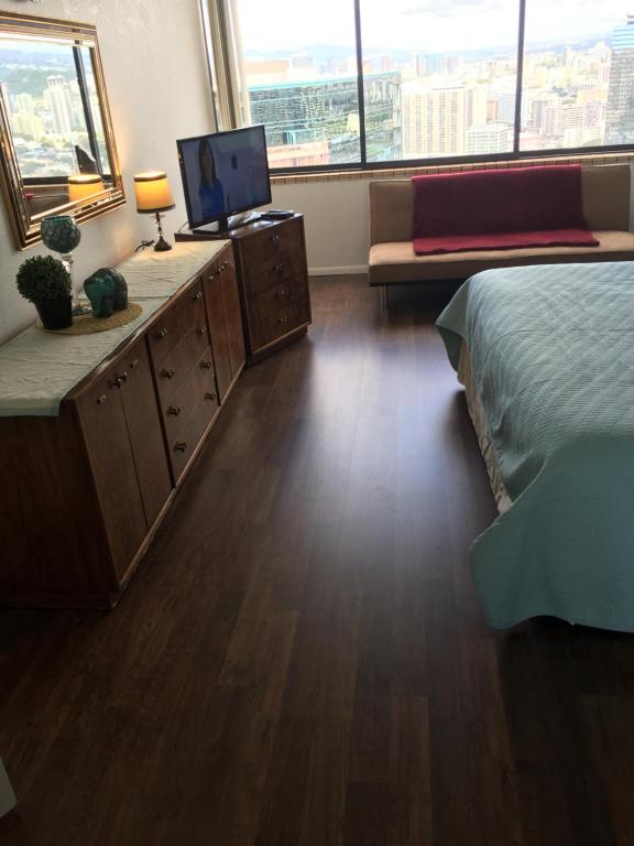 Schlafzimmer mit einem Bett und einem TV auf einem Schreibtisch in der Unterkunft Hawaiian Monarch Penthouse 401 by Hawaii Ocean Club in Honolulu