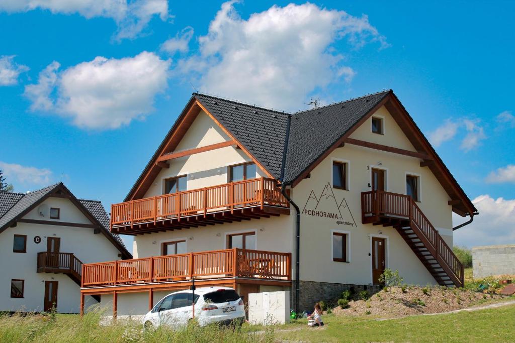 a large white house with a balcony and a car at Apartmany Podhorama in Vaclavov u Bruntalu