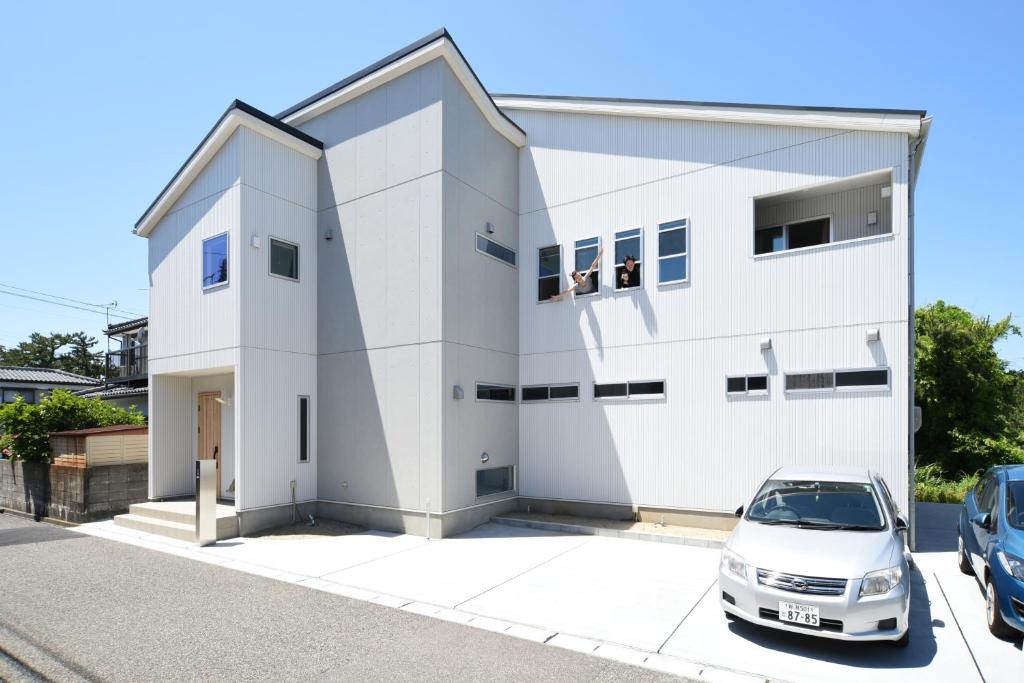 una casa blanca con un coche aparcado delante de ella en Guesthouse ORI ORI, en Niigata