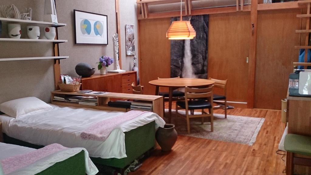 Schlafzimmer mit einem Bett und einem Tisch sowie einem Tisch und Stühlen in der Unterkunft Tajimi Guest House in Tajimi