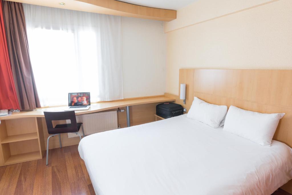 Habitación de hotel con cama, escritorio y ventana en ibis Dunkerque, en Dunkerque