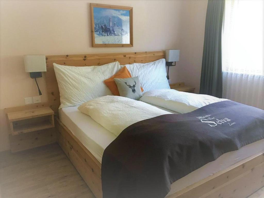 a bedroom with a bed with two lamps and a window at Hotel Pizzeria Selva in Zernez