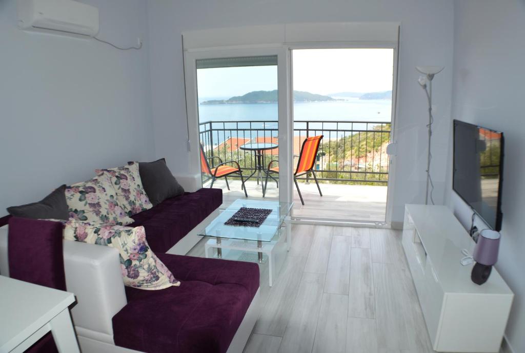 a living room with a couch and a view of the ocean at Apartments MM in Sveti Stefan