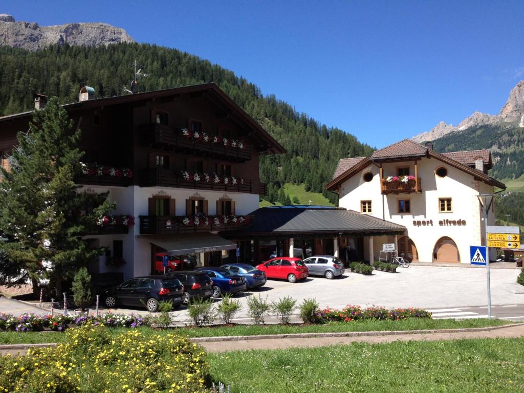 un grand bâtiment avec des voitures garées dans un parking dans l'établissement Residence Rottonara, à Corvara in Badia