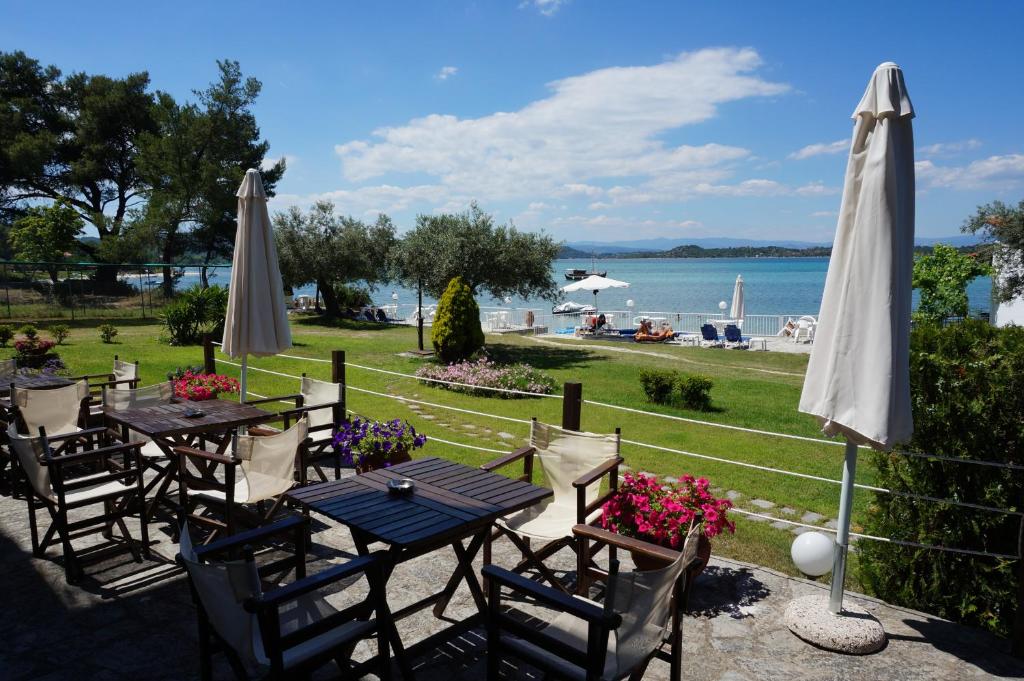 a patio with tables and umbrellas and the water at Vourvourou Hotel in Vourvourou