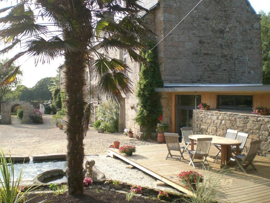 una terraza de madera con mesa y sillas frente a una casa en Manoir De Keringant, en Saint-Quay-Perros