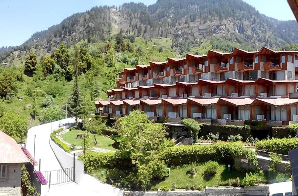 ein großes Hotel mit einem Berg im Hintergrund in der Unterkunft Manuallaya The Resort & Spa in Manali