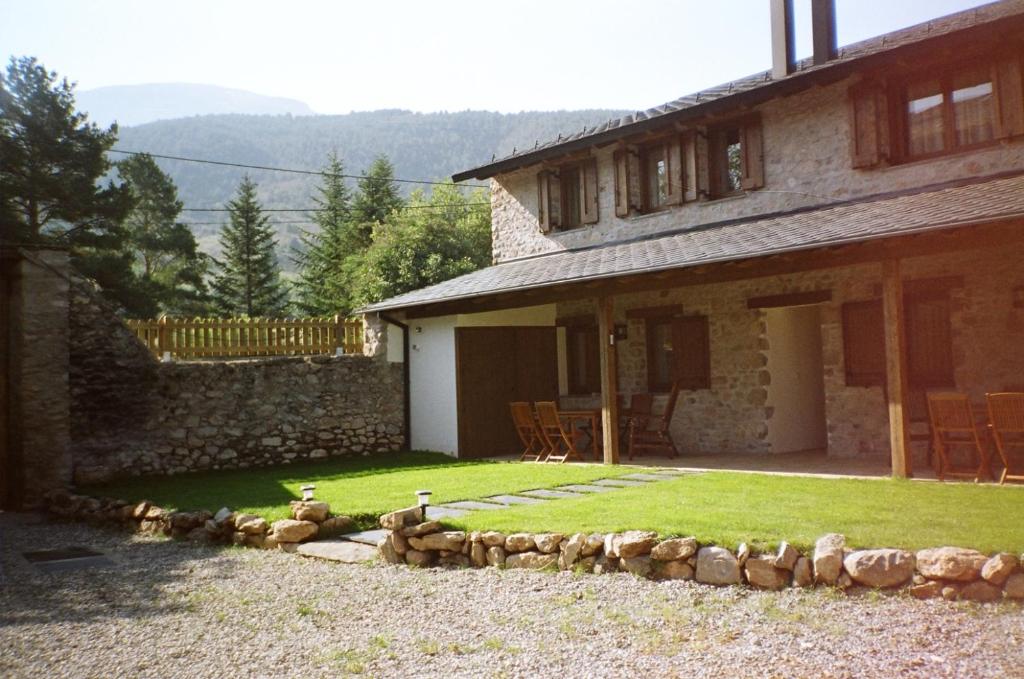 una casa de piedra con un patio con sillas delante en Cal Pedrals, en Puigcerdà