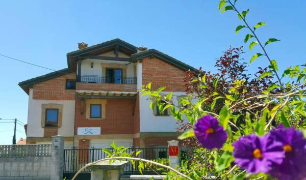 ein Backsteinhaus mit Blumen davor in der Unterkunft Apartamentos Copi Villa de Suances in Suances