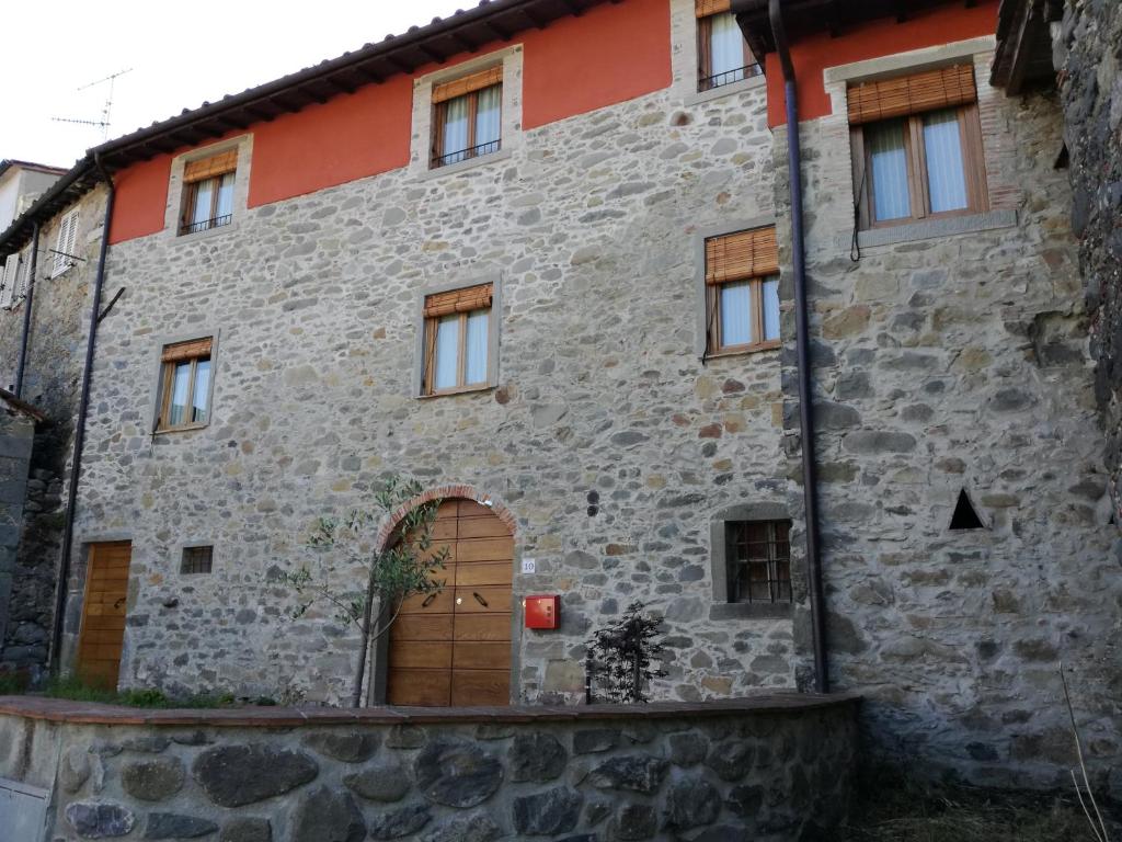 un antiguo edificio de piedra con puerta de madera en B & B Via di Mezzo en Coreglia Antelminelli