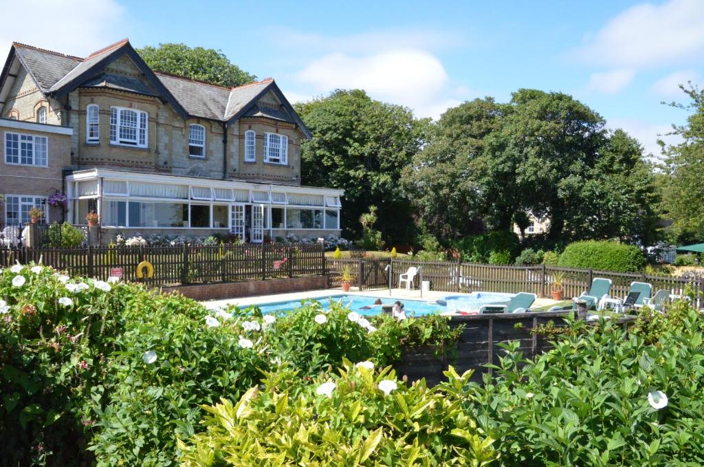 a house that has a pool and lawn furniture in it at Luccombe Manor Country House Hotel in Shanklin