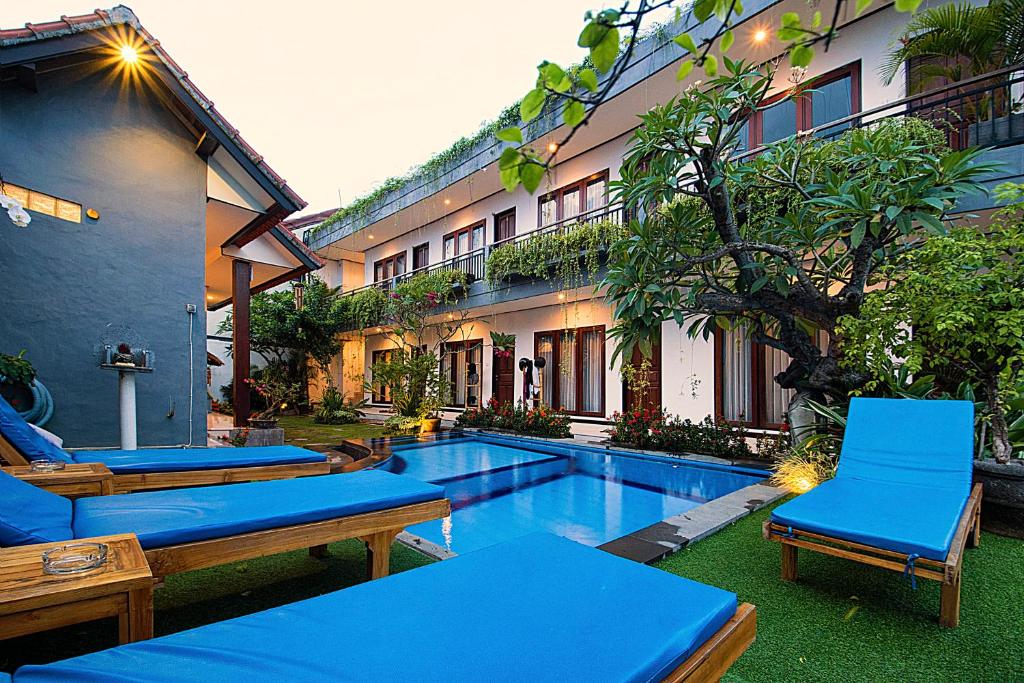 a resort with a pool and chairs and a building at Bali Full Moon Guest House in Canggu