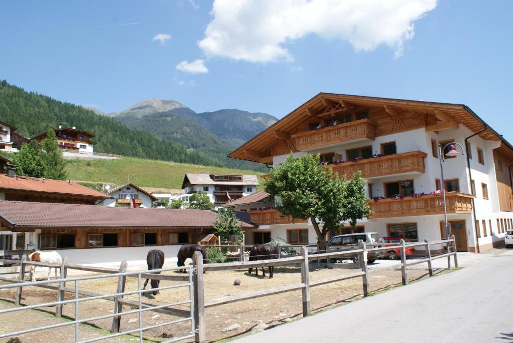 a building with a fence and horses in front of it at Singerhof in Fulpmes