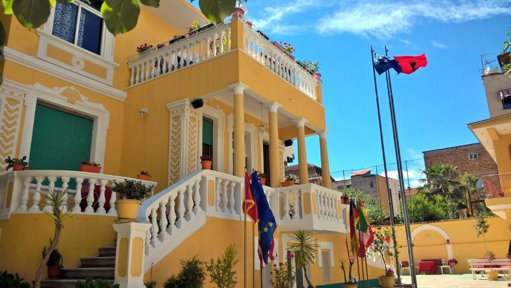 ein gelbes Gebäude mit Flaggen davor in der Unterkunft HOTEL VILA 15 - CENTER in Tirana