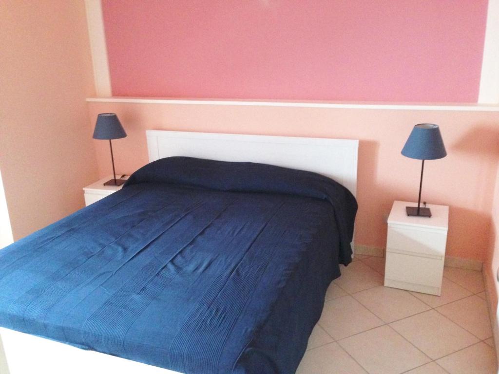 カーポ・ドルランドにあるCasa degli Agrumiのベッドルーム1室(青い毛布とランプ2つ付)