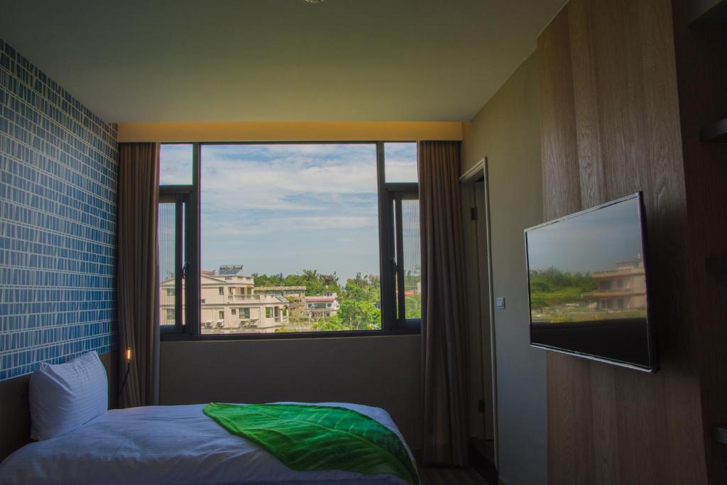 um quarto com uma janela, uma cama e uma televisão em San Yuan Guest House em Jinning