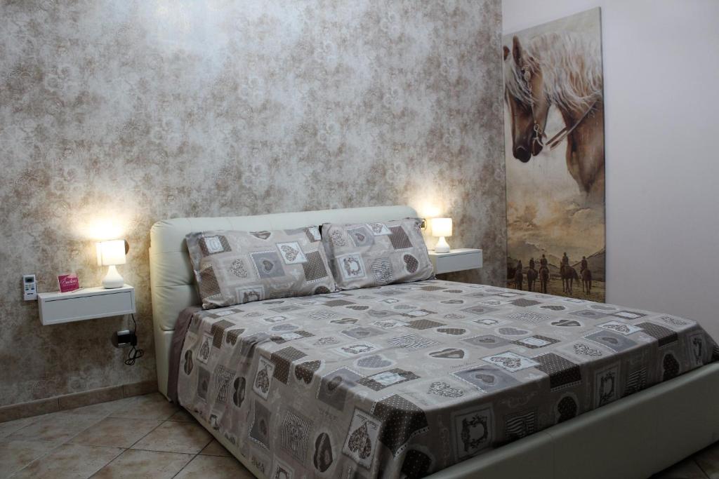 a bedroom with a bed with two lamps and a painting at Emotions in Fiumicino