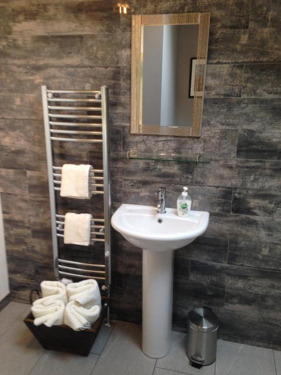 a bathroom with a sink and a mirror and towels at Pinetree Lodge Druridge Bay in Amble