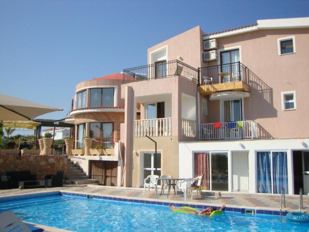 a building with a swimming pool in front of a house at Bella Rosa hotel Cyprus in Coral Bay