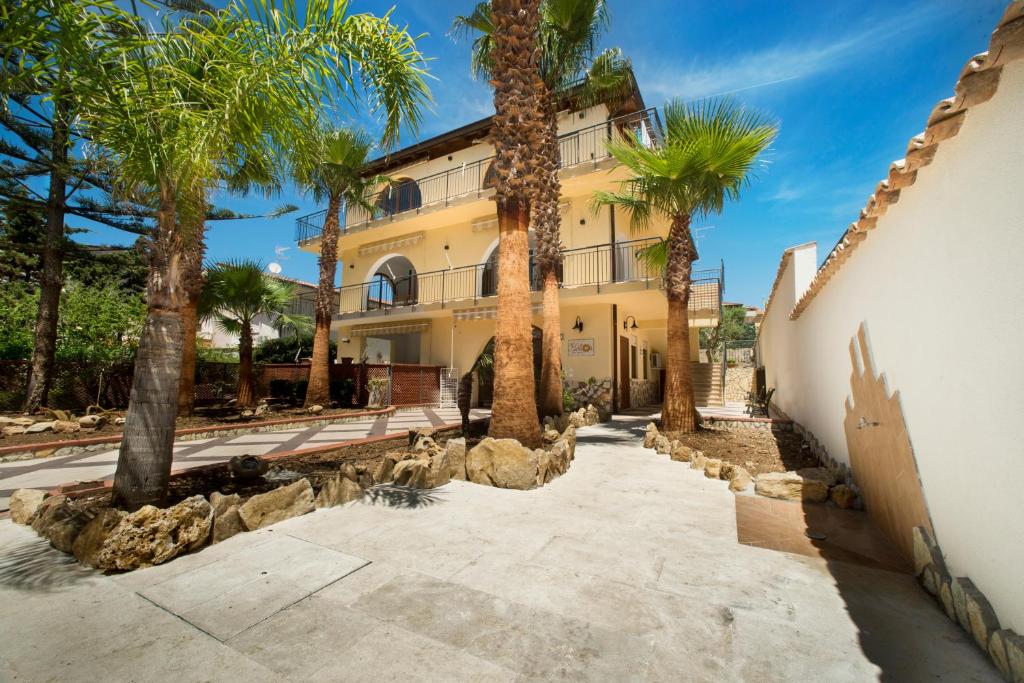 una vista esterna di una casa con palme di Helios Casa Vacanze ad Alcamo Marina