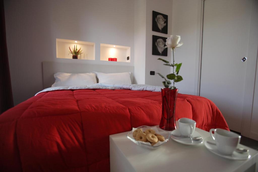 a bedroom with a red bed with a table with a vase at Le Formiche in Milazzo