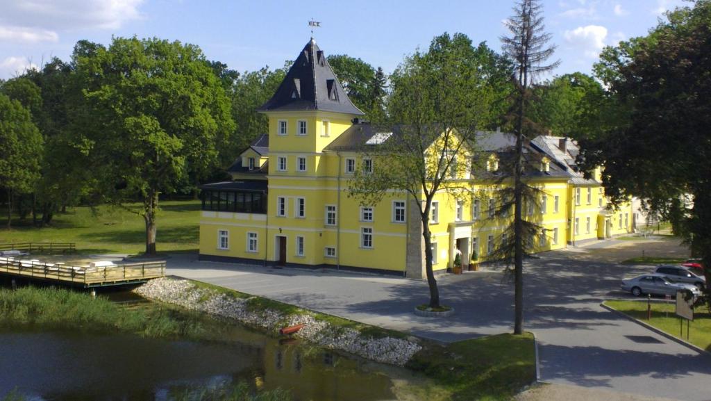 una casa amarilla junto a un río con un puente en Pałac Lucja, en Zakrzów
