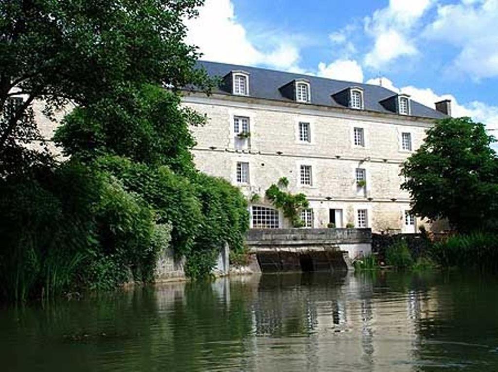 un gran edificio junto a una masa de agua en Le Moulin de Poilly, en Poilly-sur-Serein