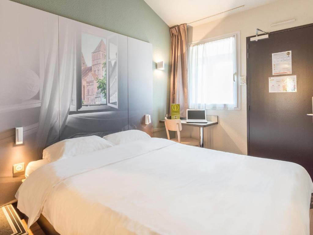 a bedroom with a large white bed and a window at B&B HOTEL Strasbourg Sud Geispolsheim in Geispolsheim