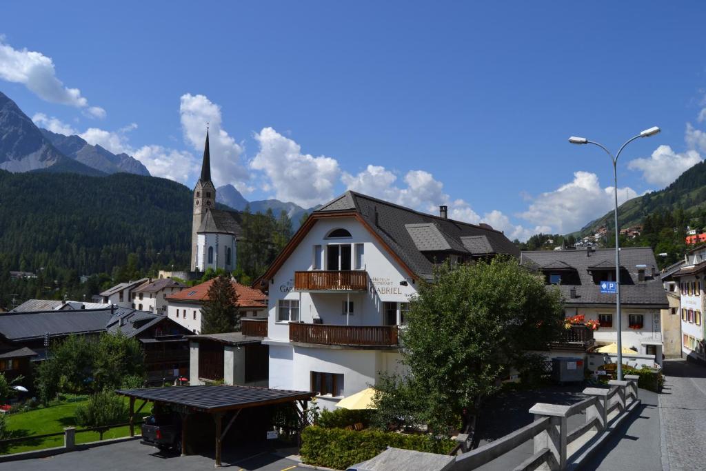 Une petite ville avec une église dans les montagnes dans l'établissement Hotel Restaurant GABRIEL, à Scuol