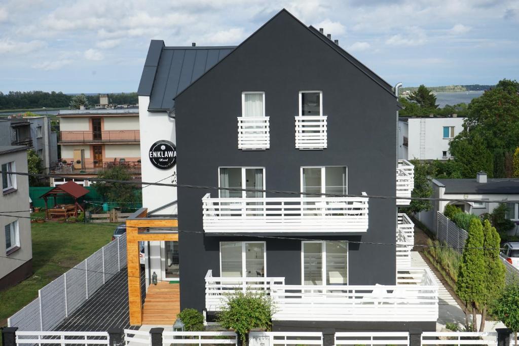 ブワディスワボボにあるEnklawa Nord Bałtycki Chillout Houseの白いバルコニー付きの黒い家