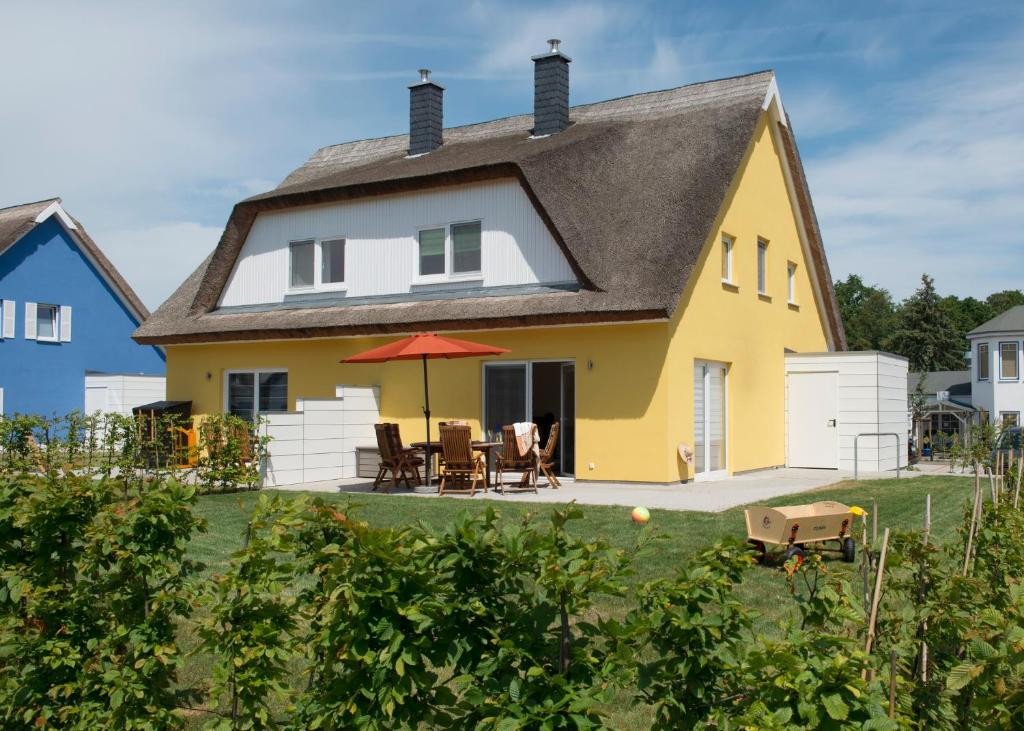 ein gelbes und weißes Haus mit einem Tisch und Stühlen in der Unterkunft Ferienhaus Küstensegler in Breege