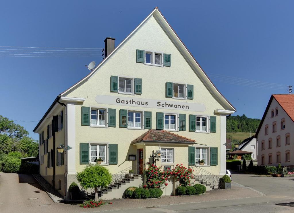 ein großes weißes Haus mit grünen Rollläden in der Unterkunft Gasthaus Schwanen in Stühlingen
