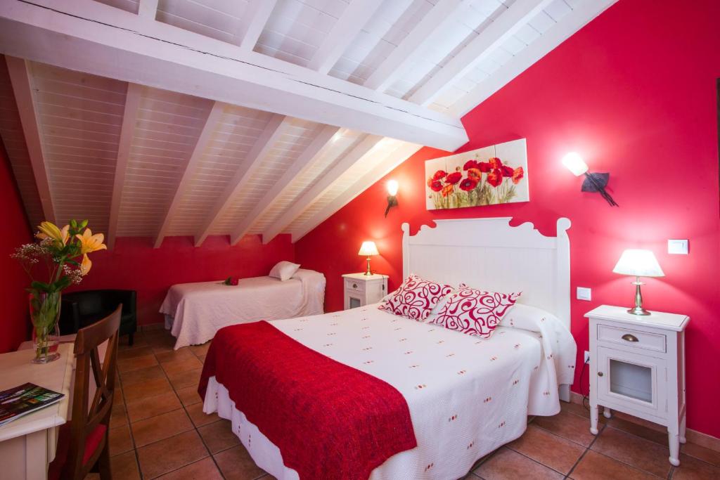 een rode slaapkamer met een wit bed en rode muren bij Posada Las Tres Mentiras de Santillana del Mar in Santillana del Mar