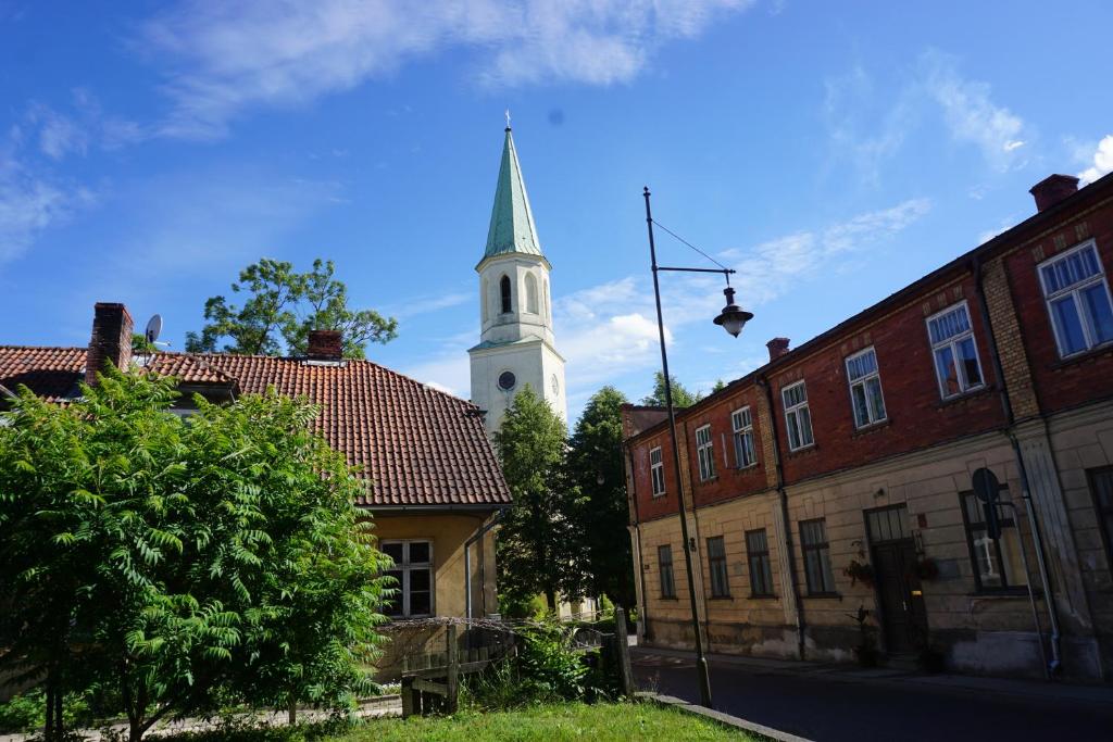 a church with a steeple in the background with buildings at Pilskalnu hostelis in Kuldīga